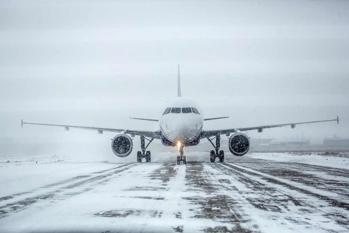 Airliner on runway in blizzard. Aircraft during taxiing during heavy snow. Passenger plane in snow at airport. Modern twin-engine passenger airplane taxiing for take off at airport during snow blizzard