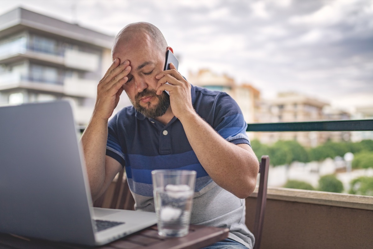 Worried and exhausted male talking on phone at balcony