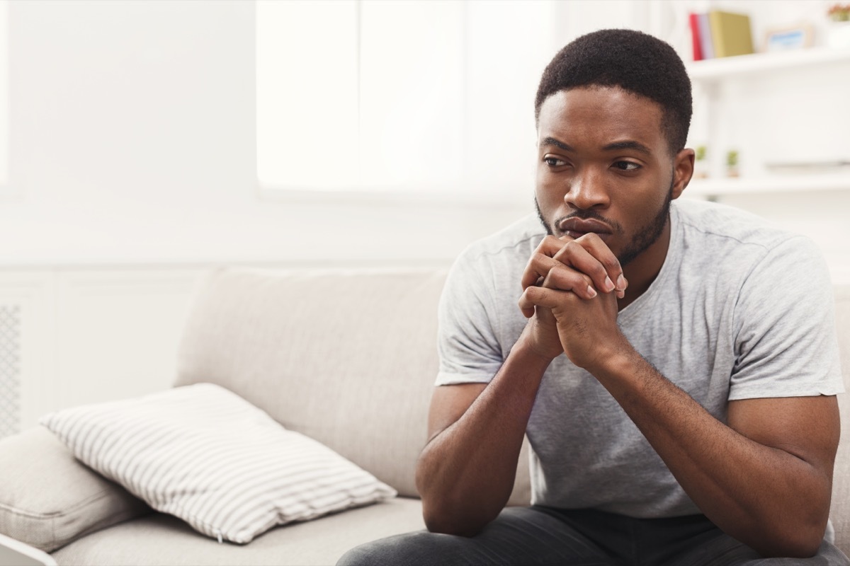 Young man sitting at home. Sad guy sitting on the couch , copy space