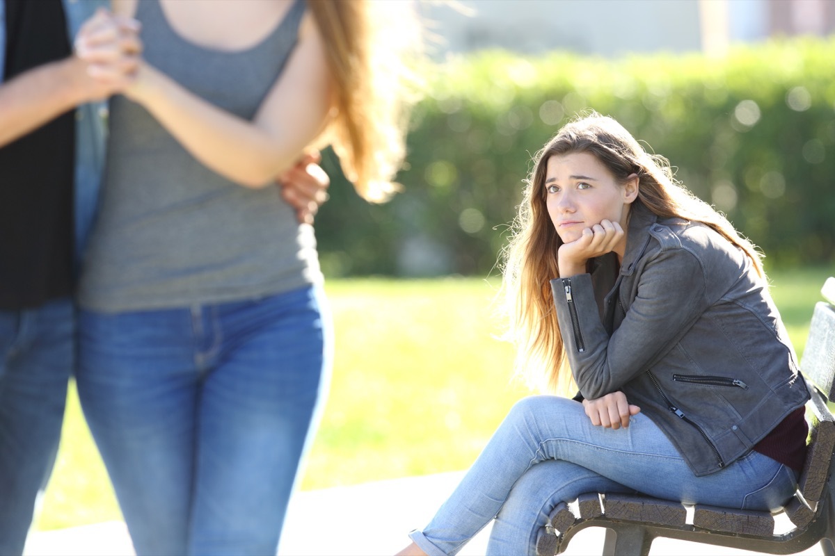 sad woman looking at couple at a park