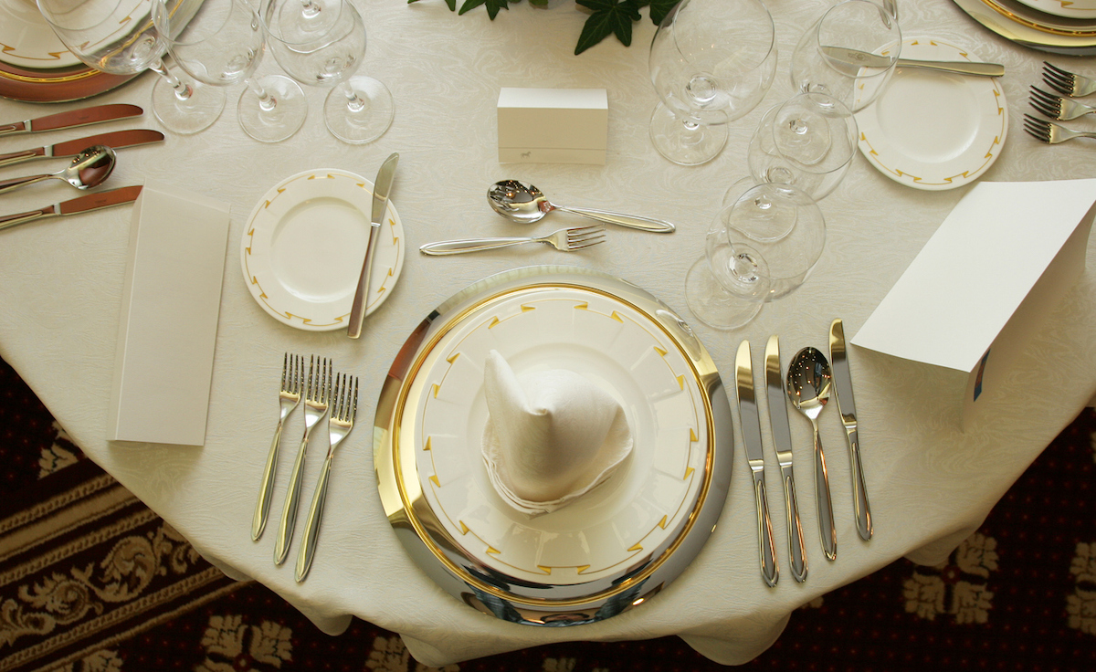 Formal table setting showing many utensils and glasses