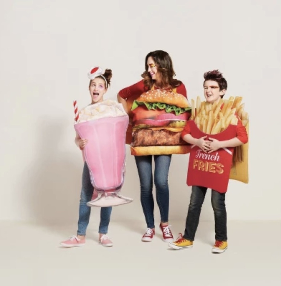 woman dressed as a hamburger, girl dressed as pink milkshake, and boy dressed as french fries, family halloween costumes