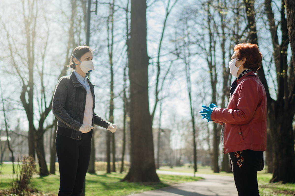 Elderly woman with protective face mask/gloves talking with a friend outside