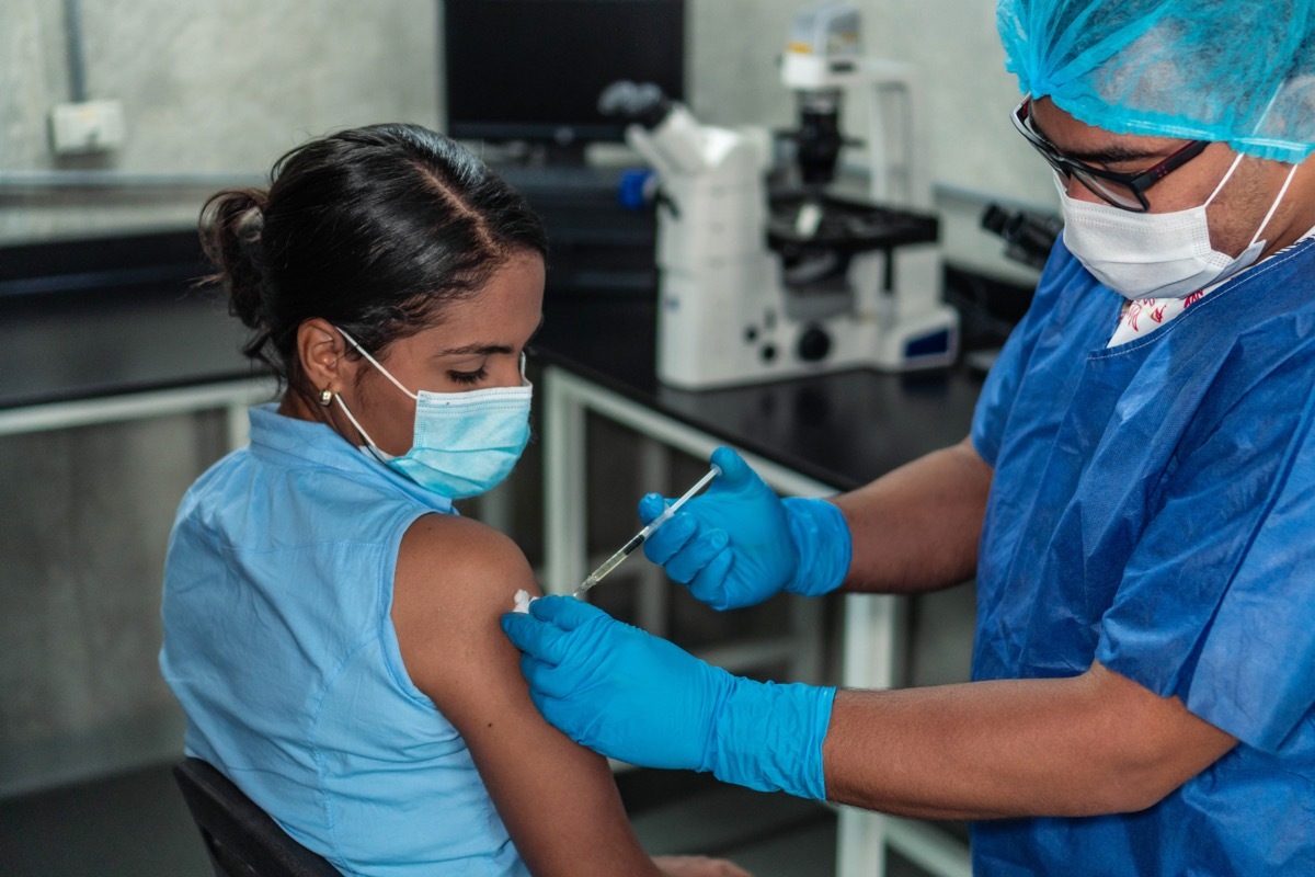 woman receives covid vaccine, wearing face mask