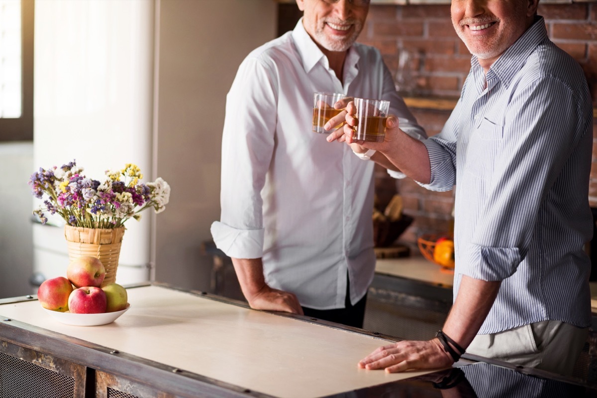 Middle-aged men smiling at the camera while having their whiskey