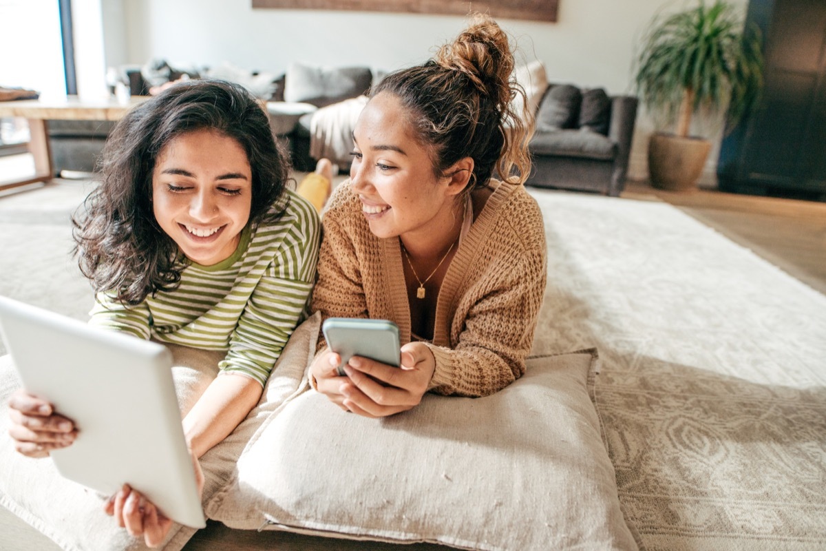 two millennial girls on the bed talking