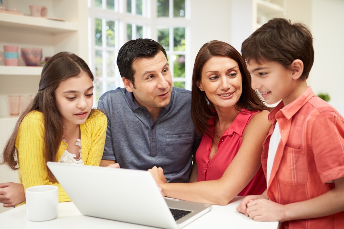 Family looking at laptop and talking in kitchen