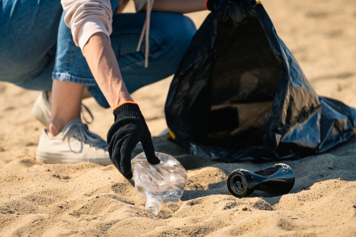 Woman volunteer cleaning area on the beach. Pollution and environmental problem concept.