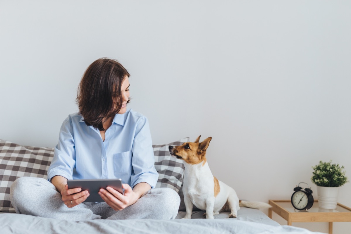 woman sitting on her bed with her small dog