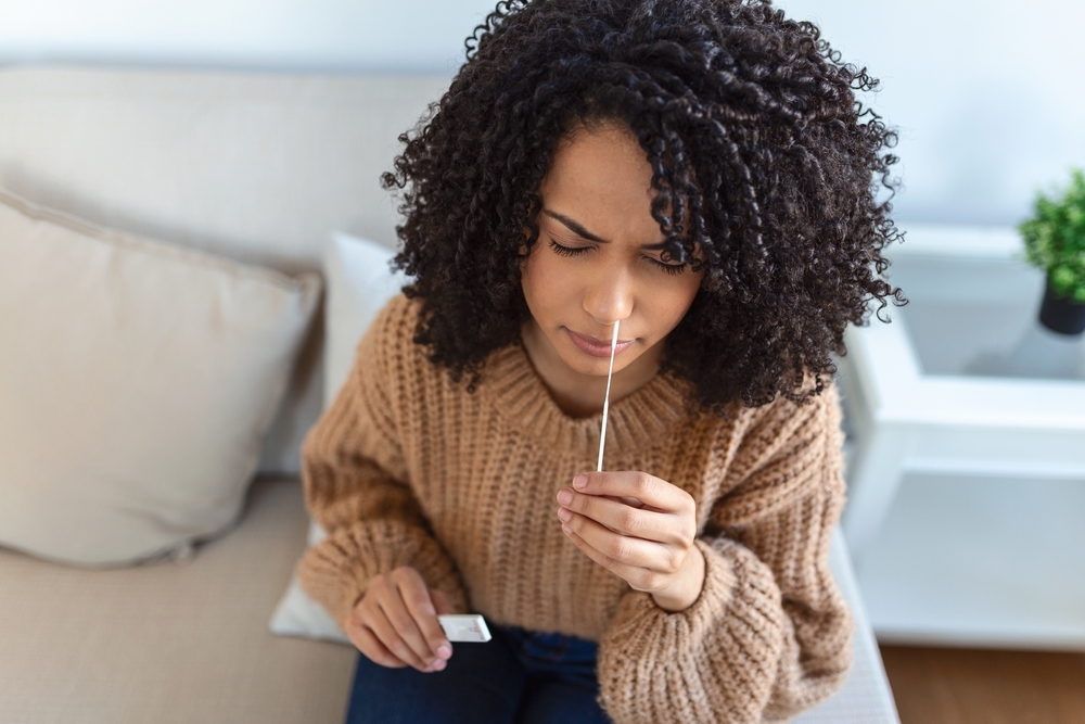 A woman taking an at-home COVID test on her couch