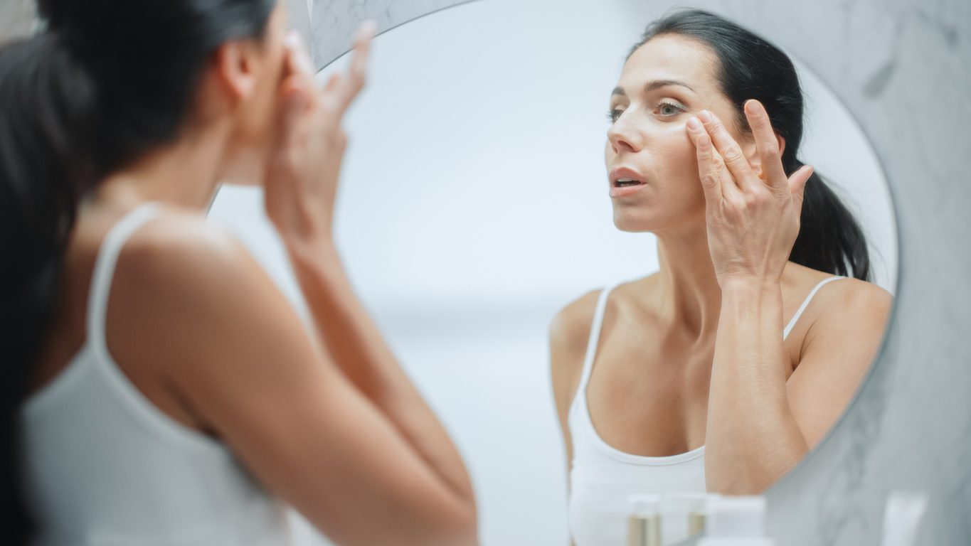 Woman looking at her skin in a mirror.