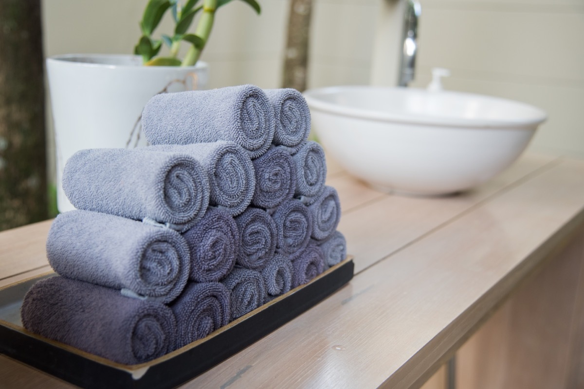 rolled towels in wooden tray at clean bathroom