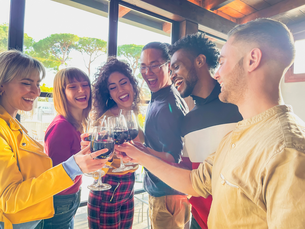 A group of young people cheersing wine glasses in a bar