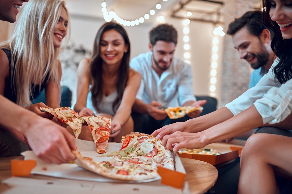 Friends hanging out and eating pizza with a lot of toppings together