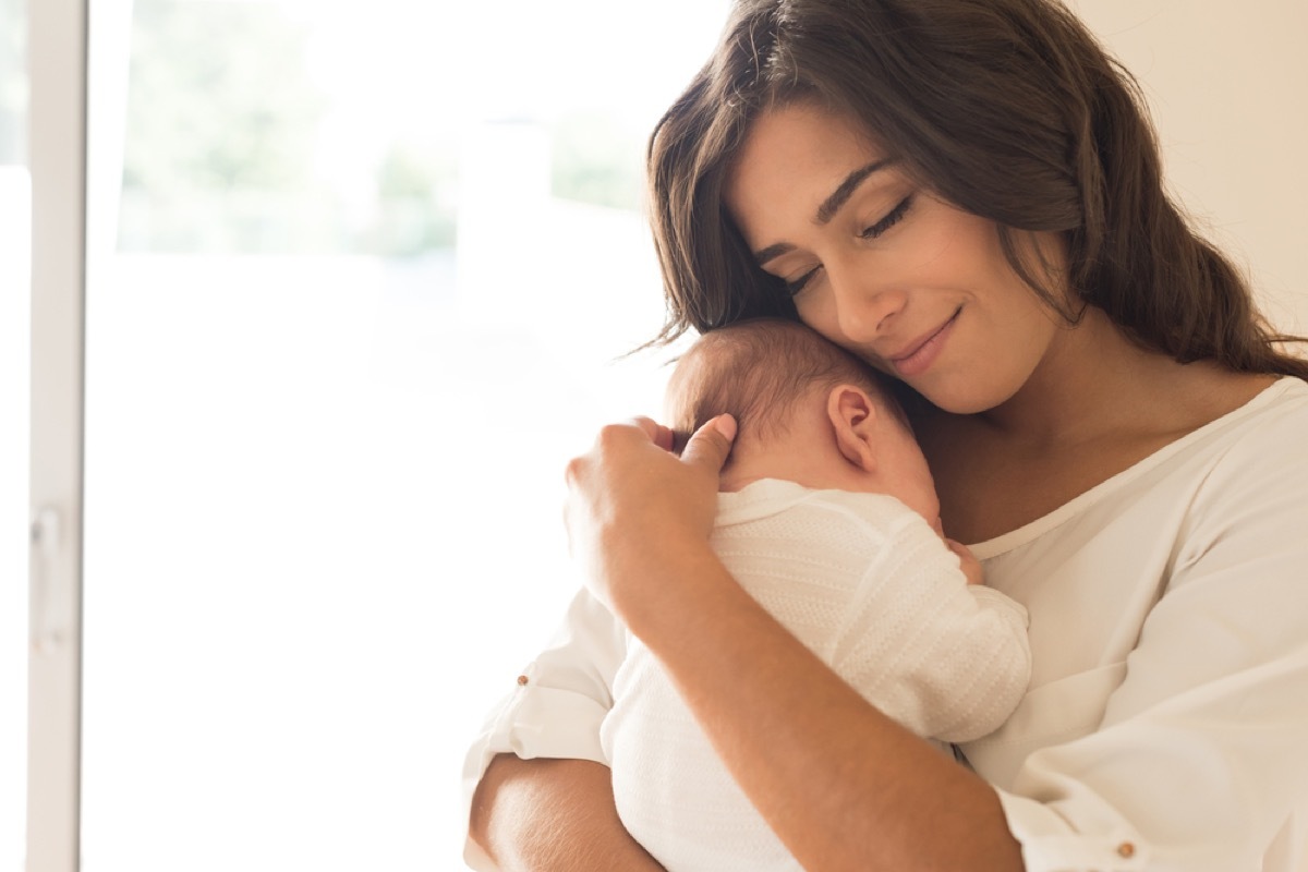 woman in white sweater holding newborn baby