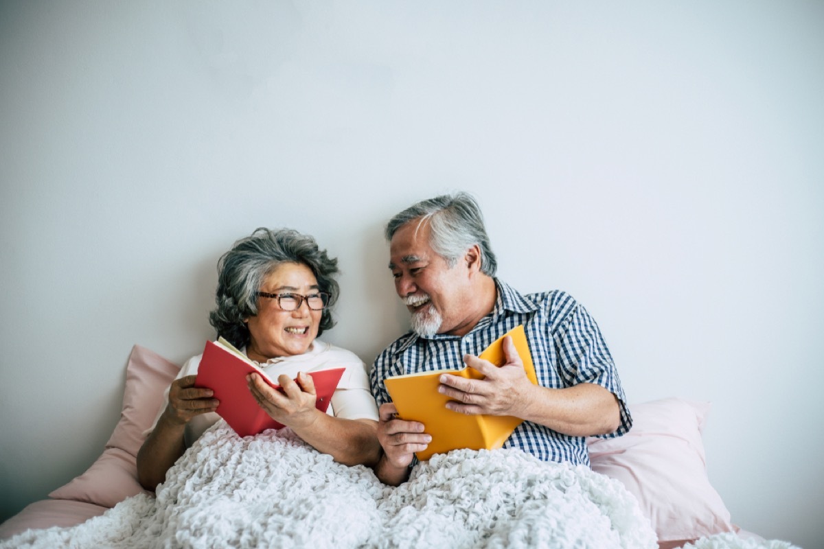 senior asian couple reading in bed