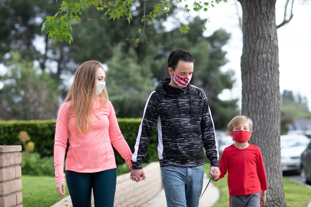 A family walking holding hands wearing face masks in the middle of pandemic