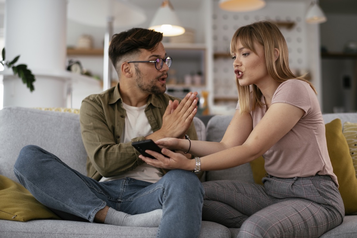 Boyfriend and girlfriend are arguing on the couch. Angry woman is yelling at her boyfriend.