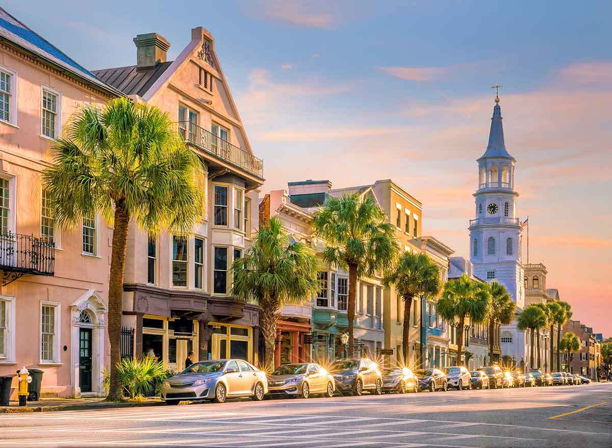 palm trees line storefronts and a church in charleston