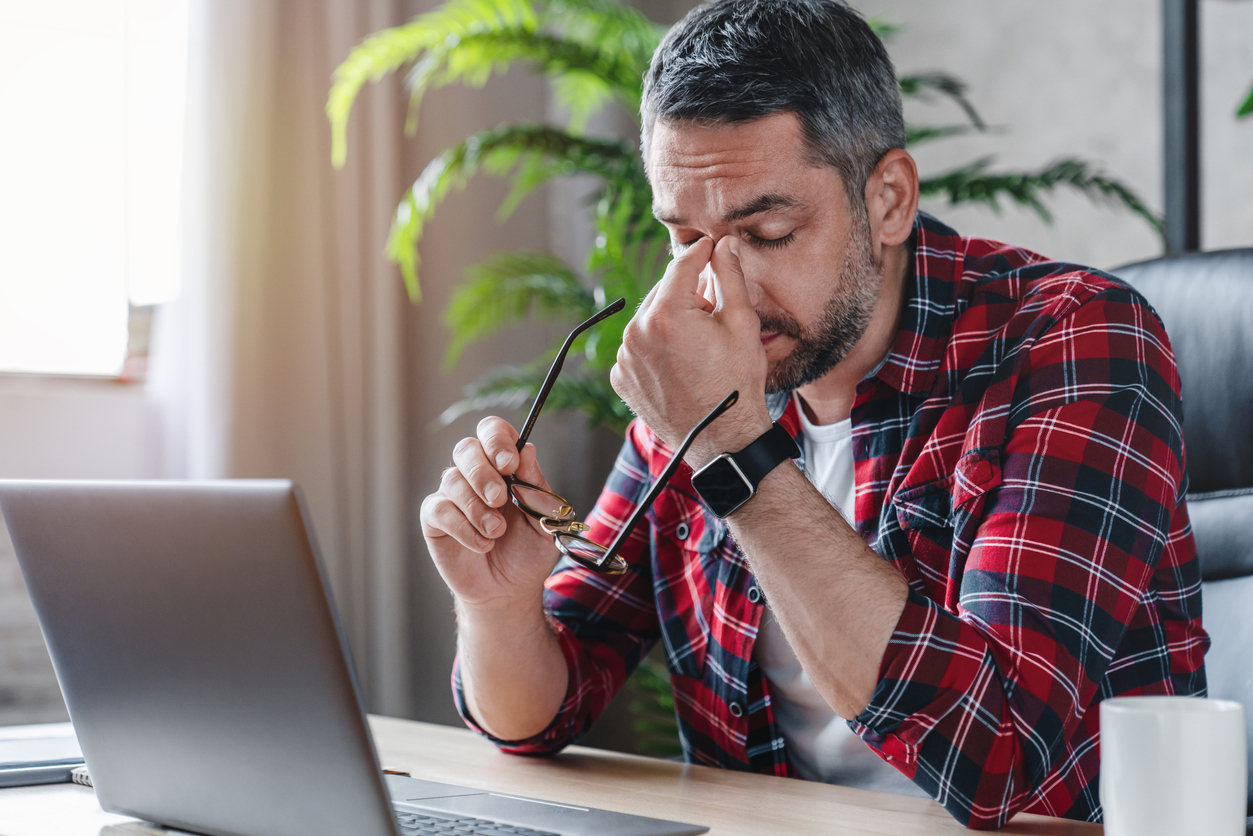 Man at his desk feeling tired.