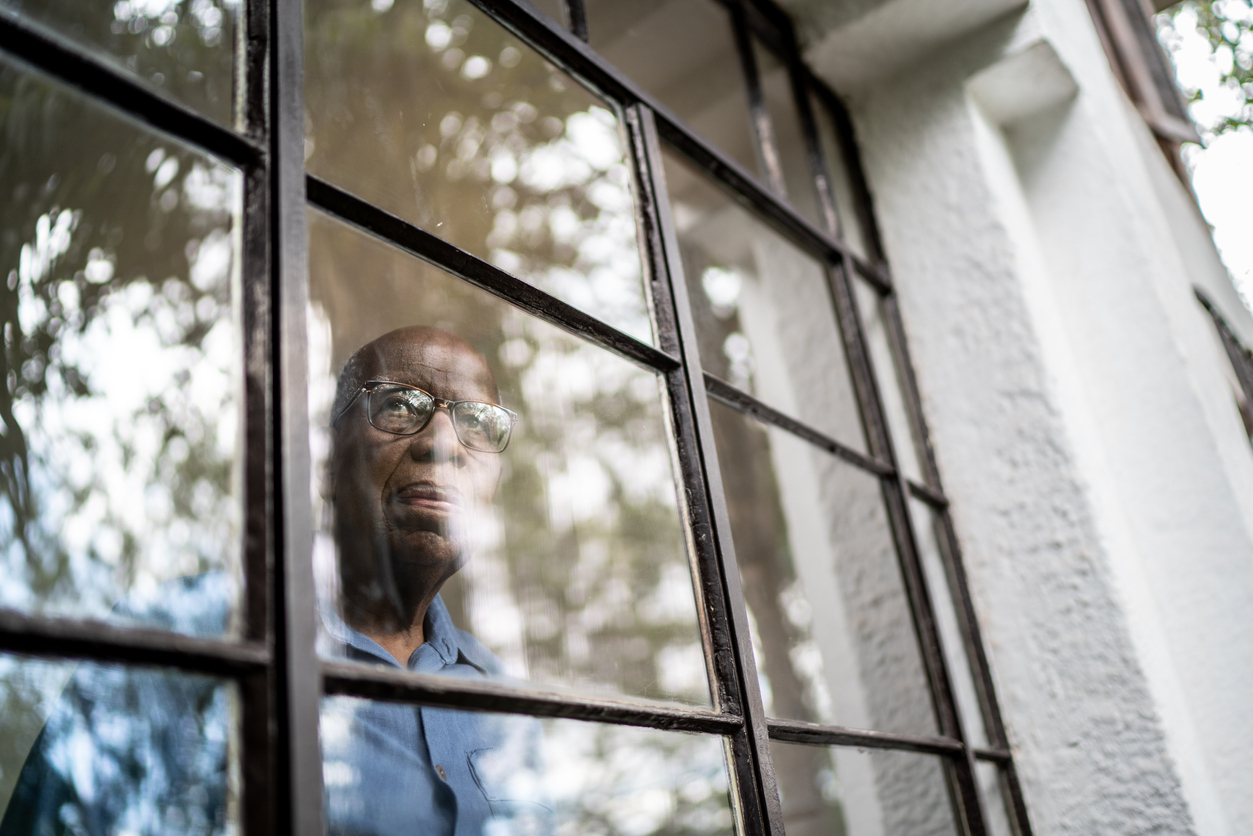 Senior man looking out of a window.