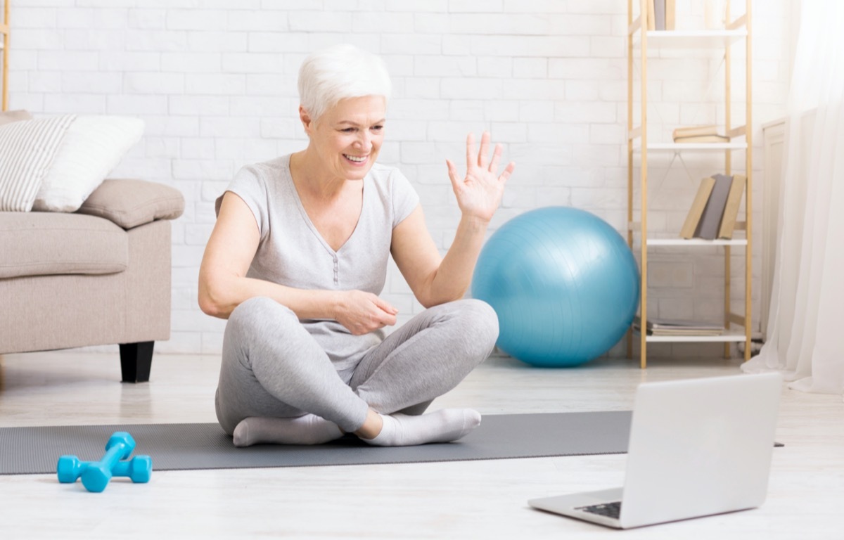 Sporty mature woman showing her training online via laptop, preparing special workout plan for senior people