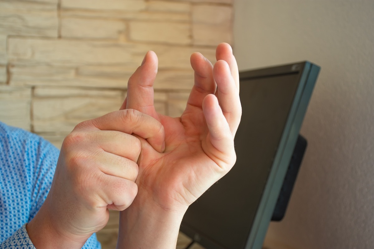 Concept photo of pain or spasm in thumb. Man hold thumb with palm of the other hand, which muscles of which are spasming or aching joints.