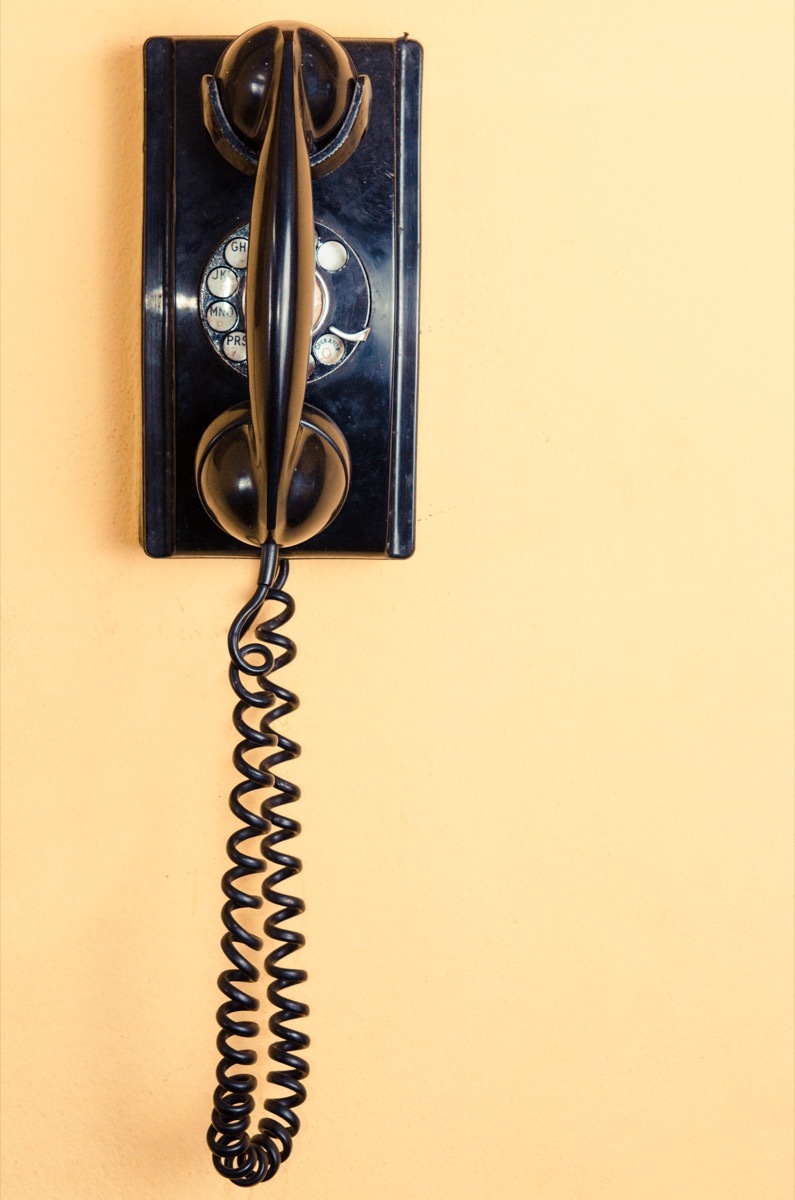 old black telephone with rotary disc on Yellow wall - Image