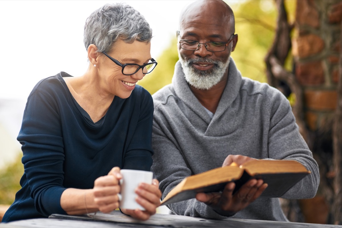 Cropped shot of an affectionate senior couple reading their bible while sitting outside