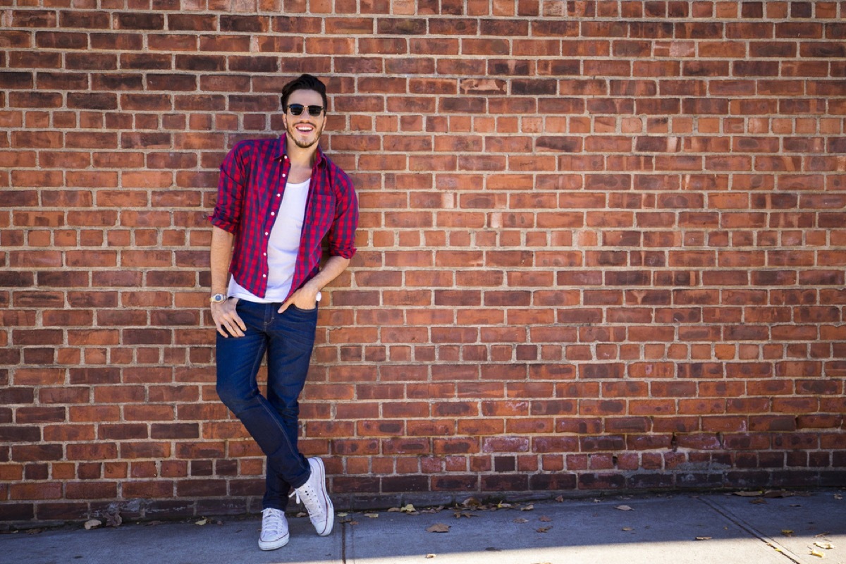 man in skinny jeans standing against brick wall, make yourself more attractive