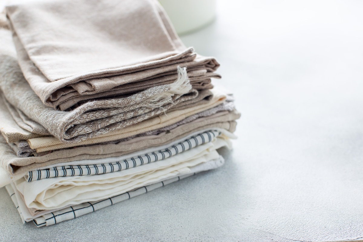 Clean kitchen textiles made of cotton and linen - napkins, towels folded on the table, horizontal, place for text