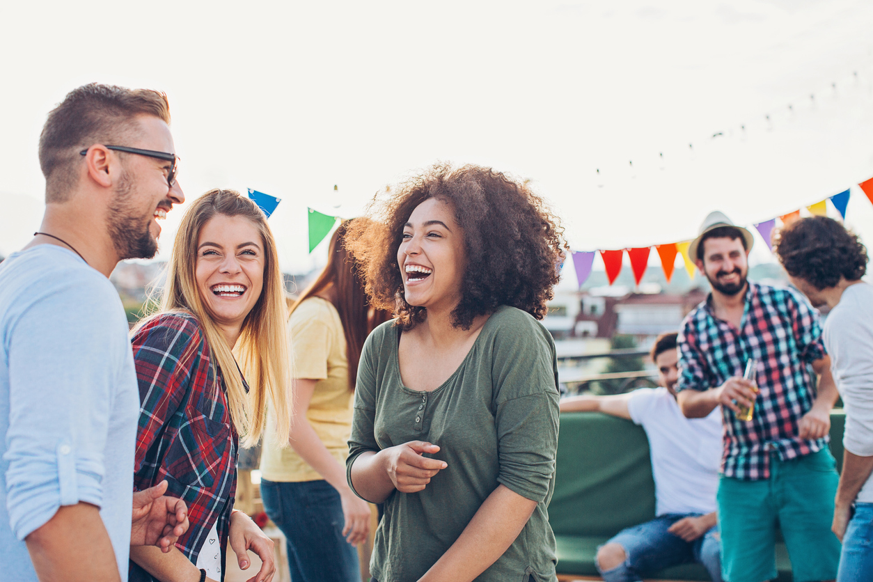 A group of young people laughing while attending a rooftop party