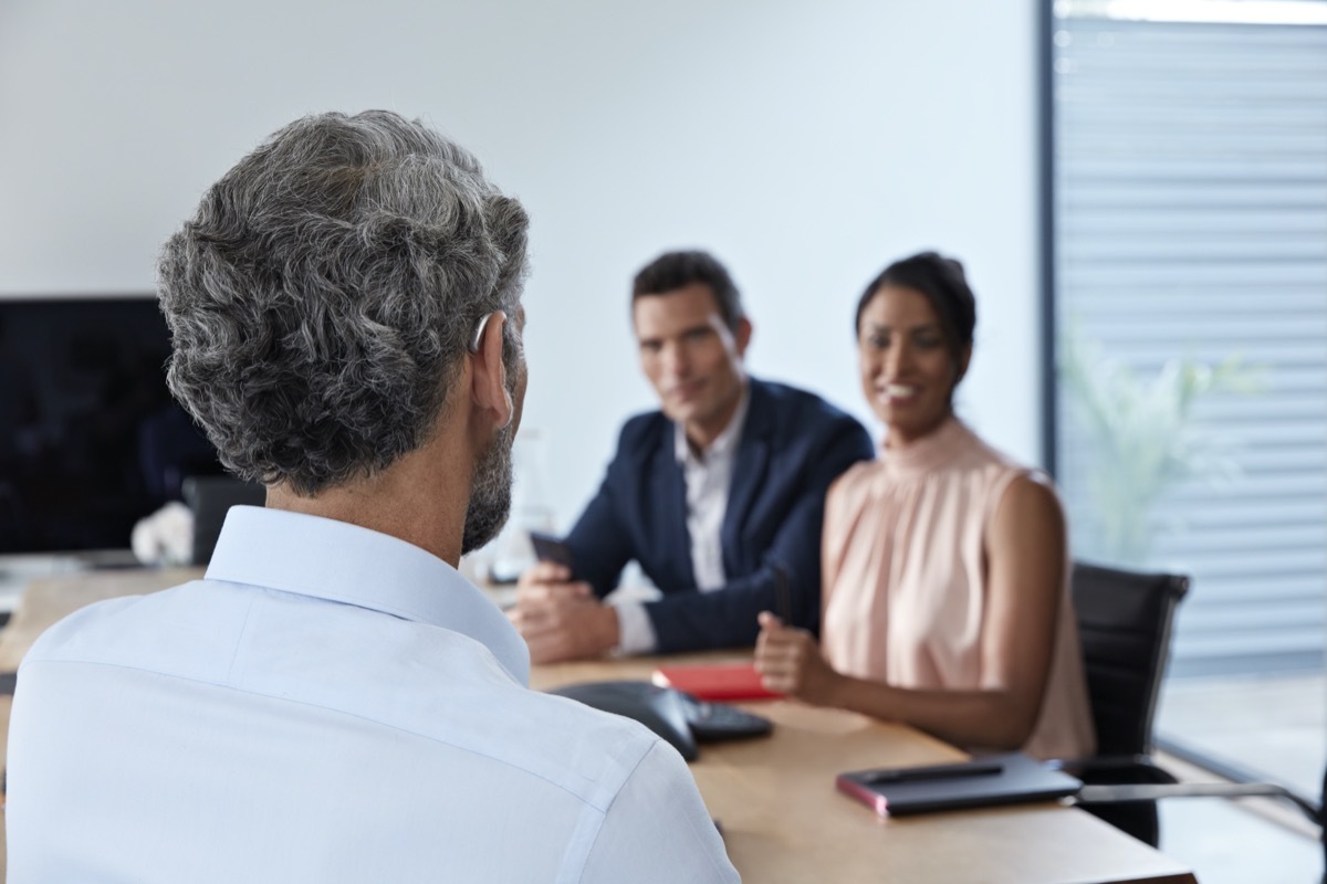 Businessman attending office conference using bluetooth hearing aid