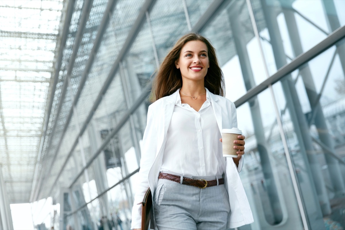 Woman Going To Work With Coffee Walking Near Office Building. Portrait Of Successful Business Woman Holding Cup Of Hot Drink In Hand On Her Way To Work On City Street health tweaks over 40