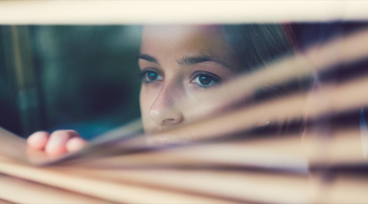 person looking through blinds