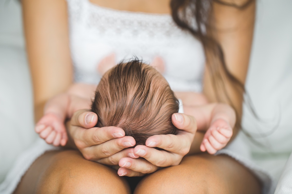 Woman holds newborn in lap, teen pregnancy