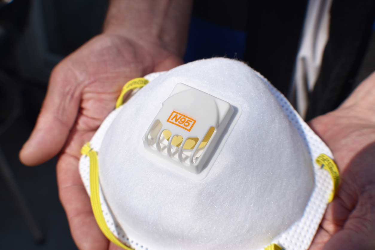 A close up of an N95 respirator protective face mask being held in someone's hands