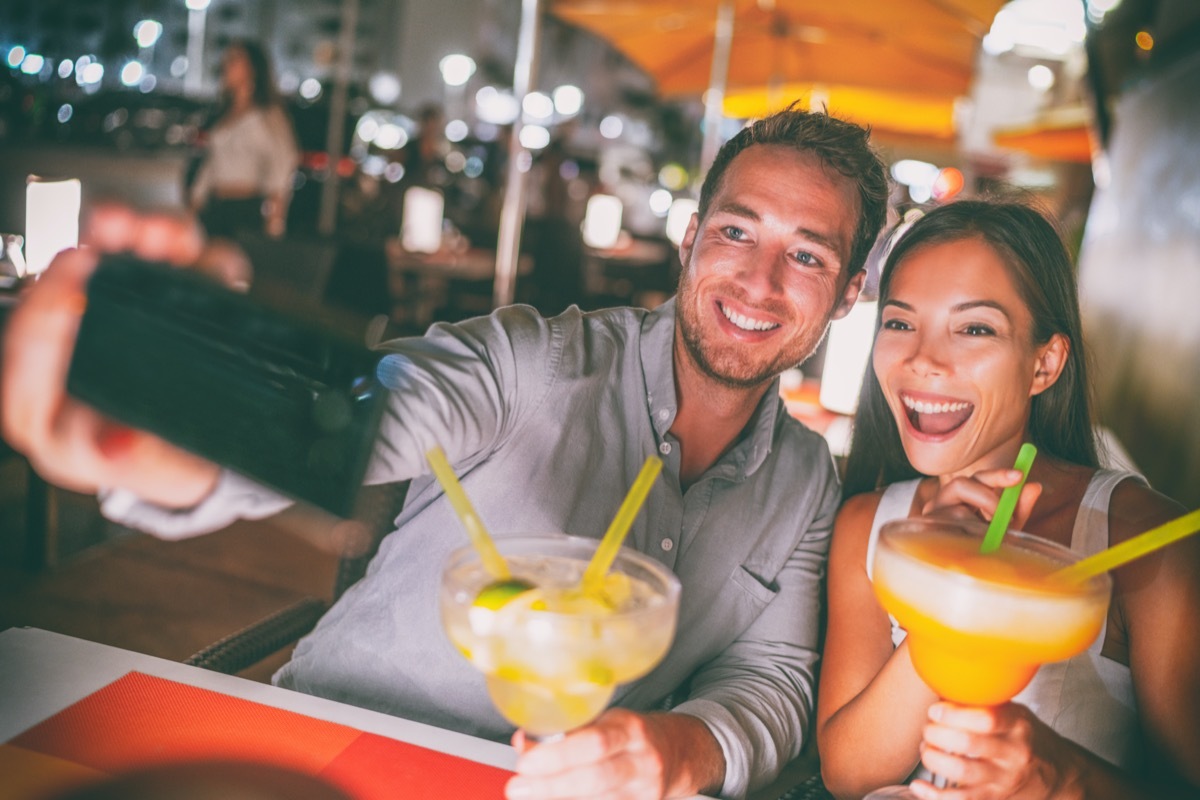 Young man and woman drinking margaritas and taking a selfie