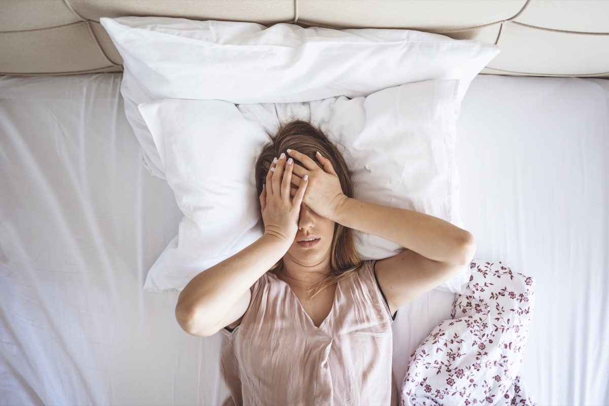 Woman on a bed with a headache.