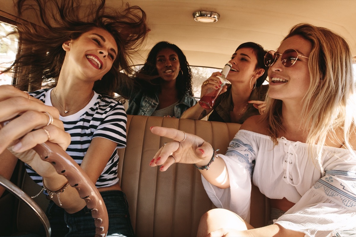 Group of women driving in a car and singing along to music