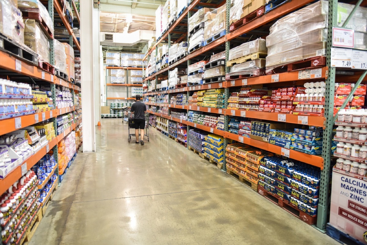 man walking down an aisle at costco