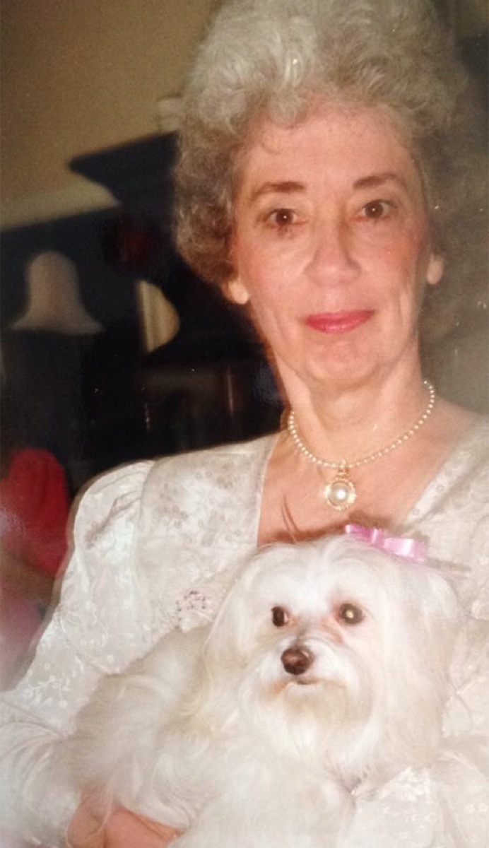 White haired grandma holds white Maltese dog, dog and owner twins