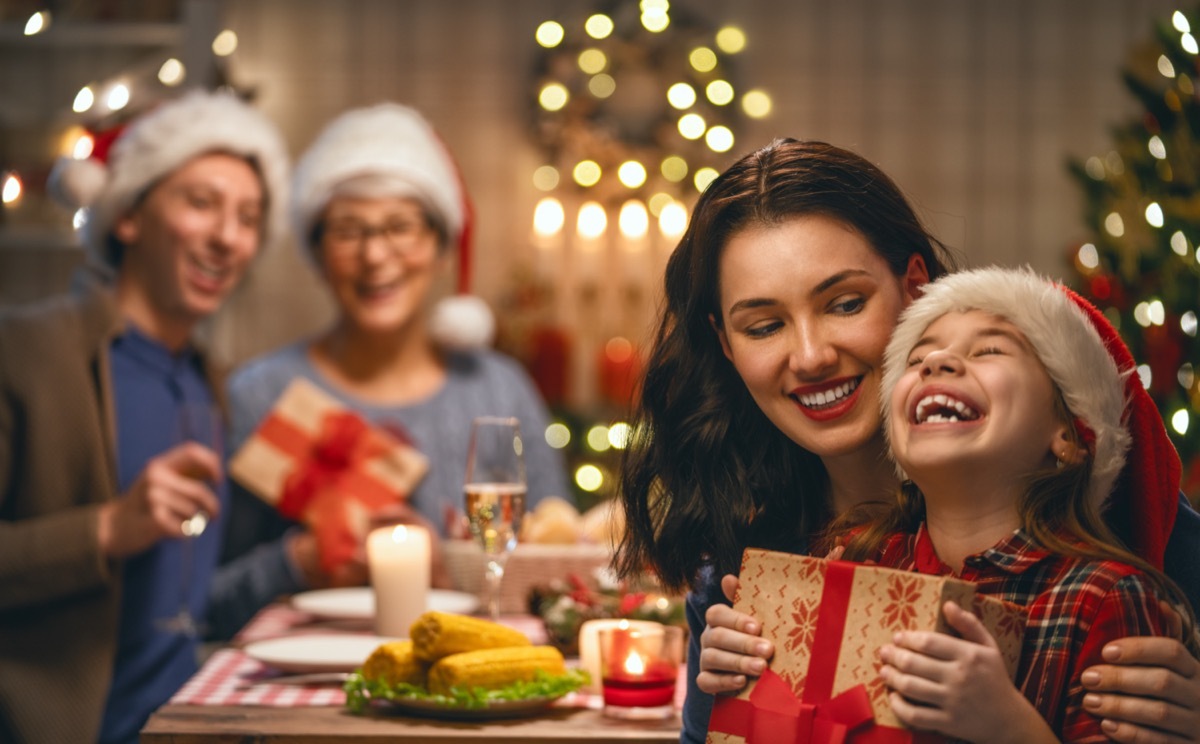 child with mother holding a gift and man and older woman in the background