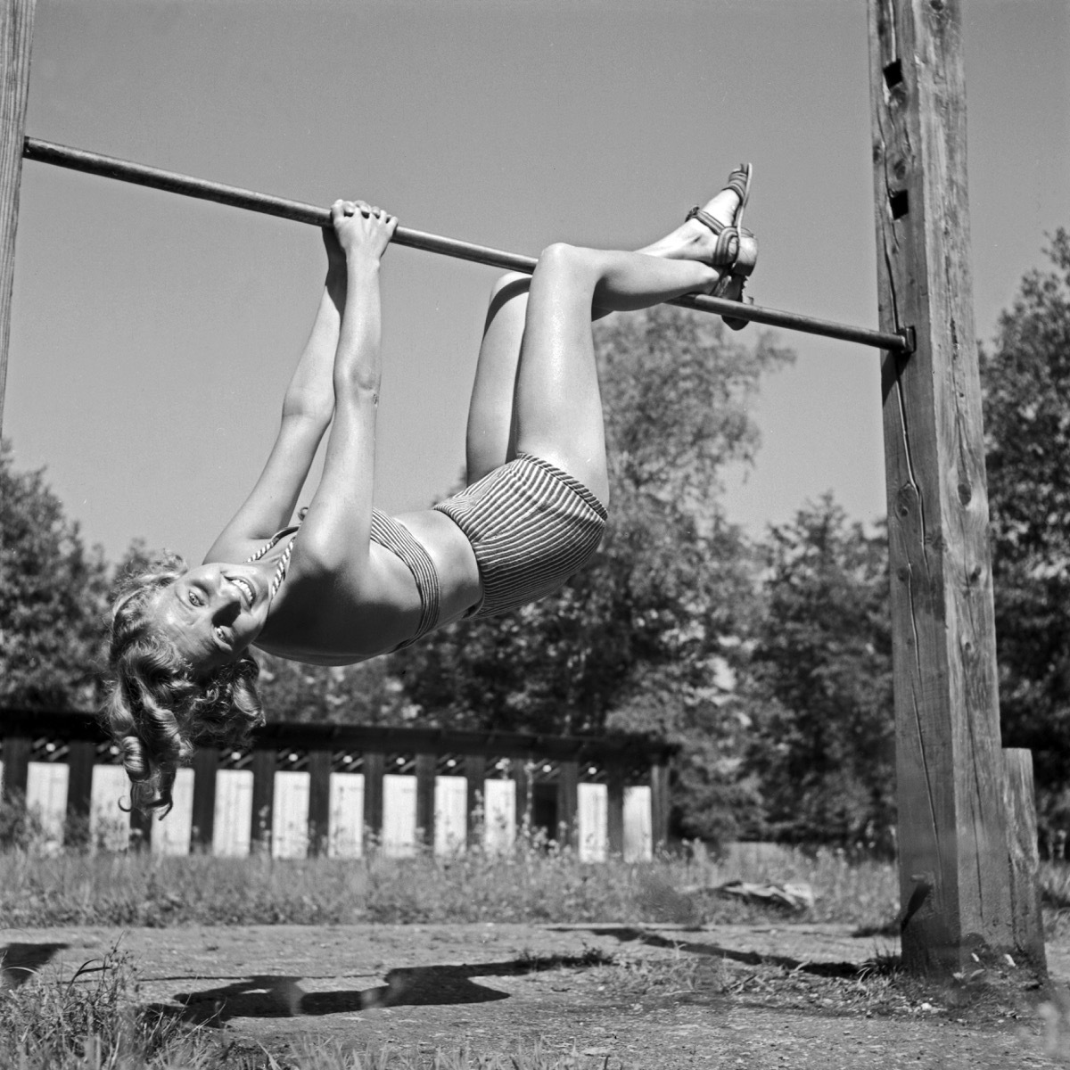 woman hanging from a bar, wearing an old bikini swimsuit, first bikini reactions