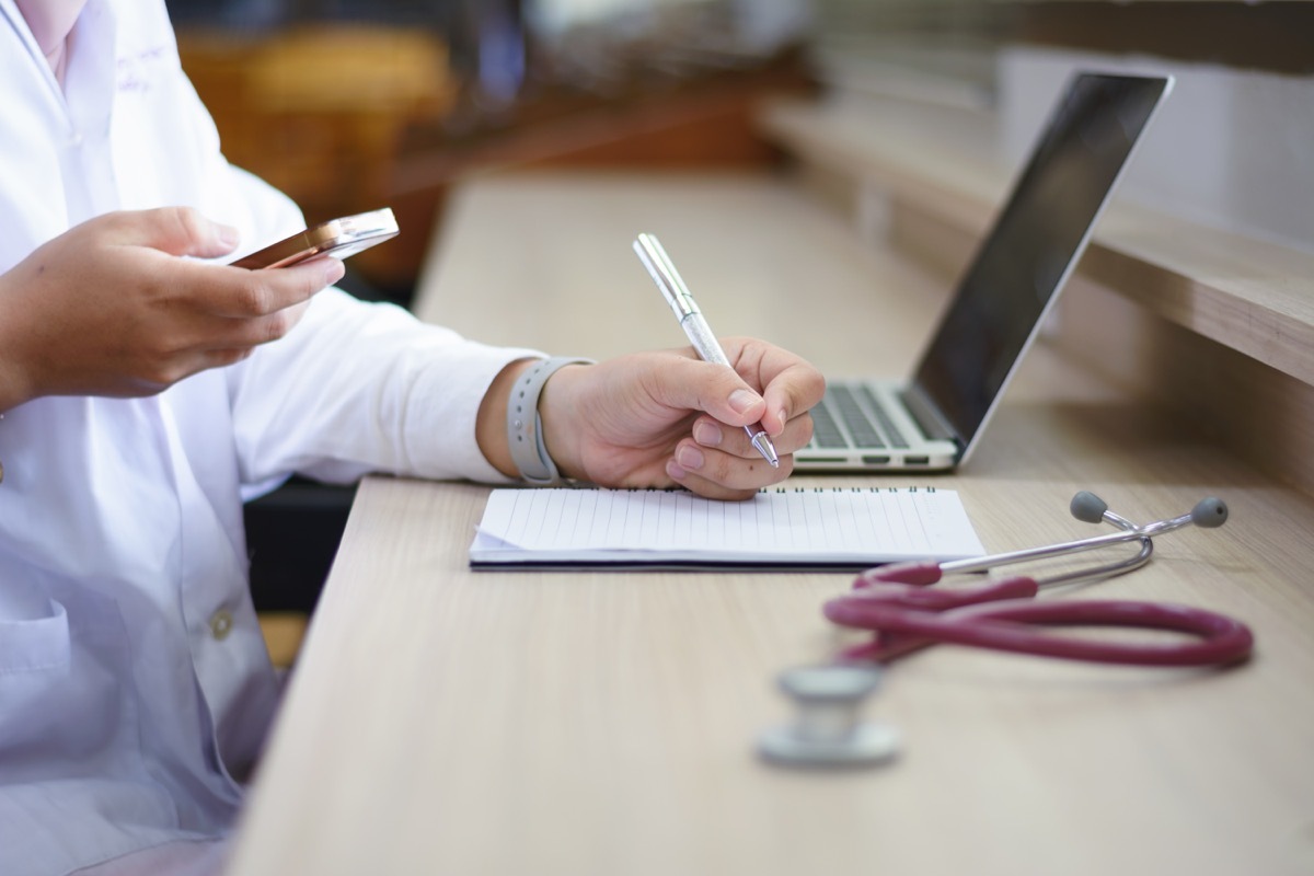 female doctors using smartphone while examining patient medical history list