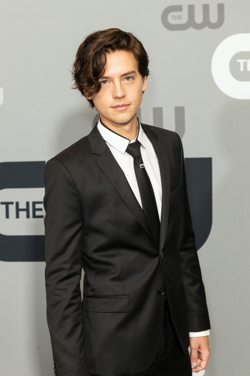 cole sprouse in black suit on red carpet in front of CW step-and-repeat