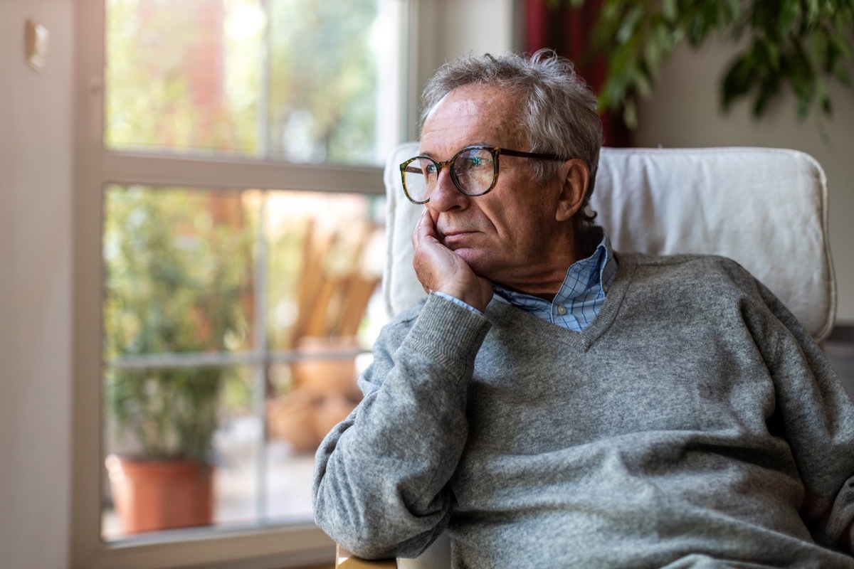 older man looking out a window at home