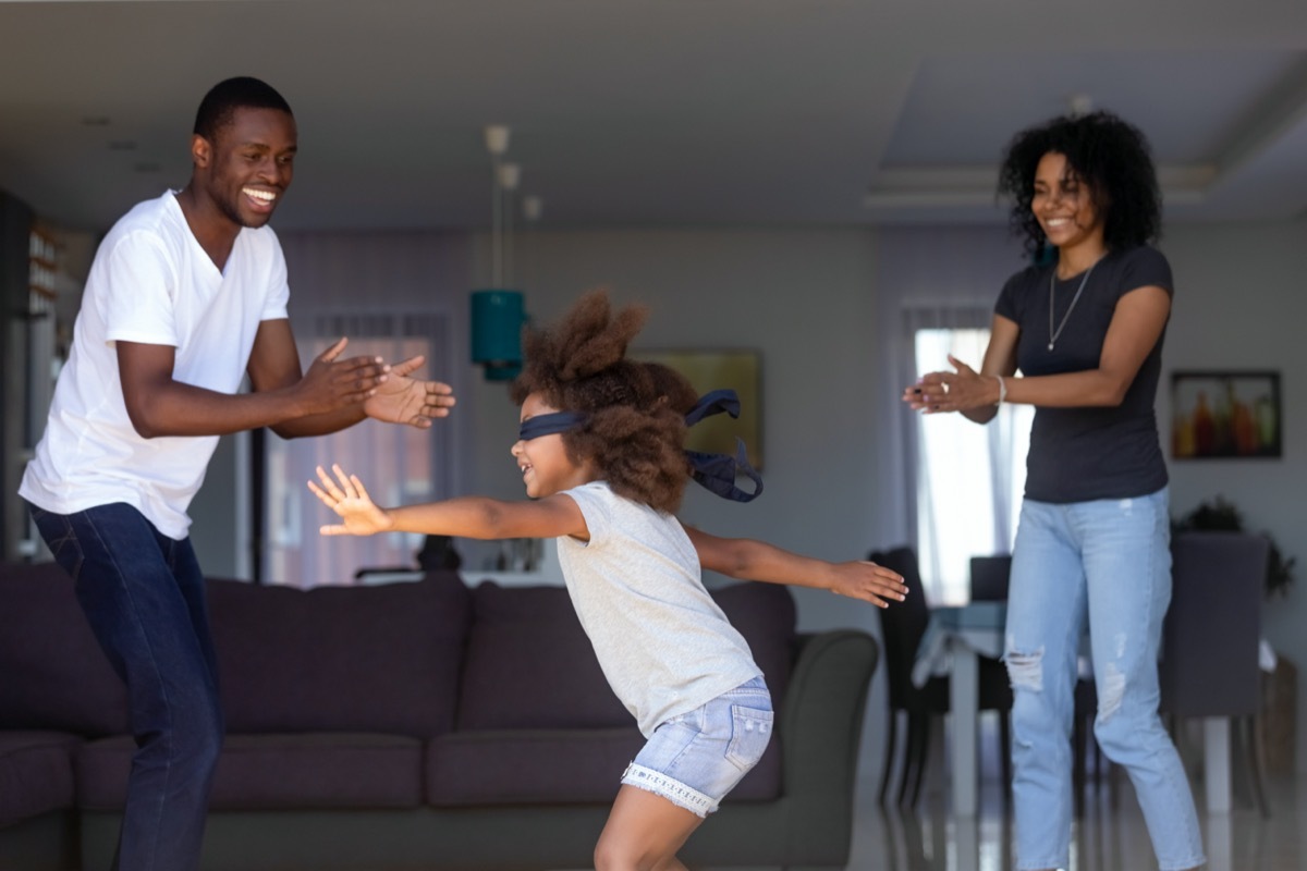 African-American parents play marco polo with their daughter wearing blindfold