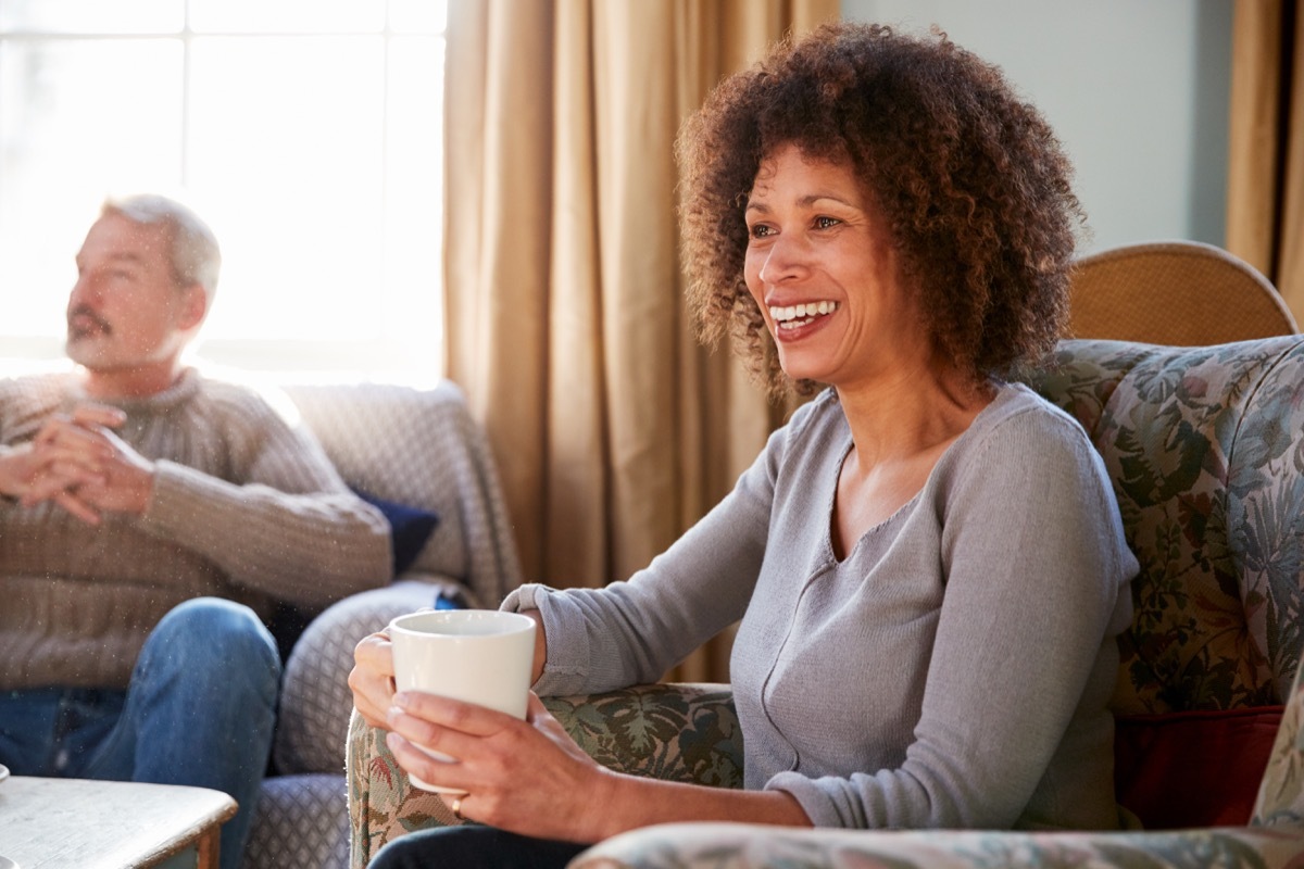 Middle Aged Couple Meeting Friends Around Table In Coffee Shop