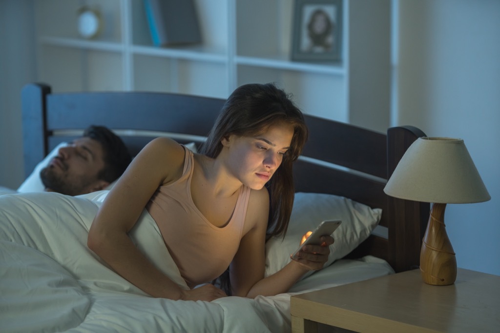 Woman in bed with her phone.